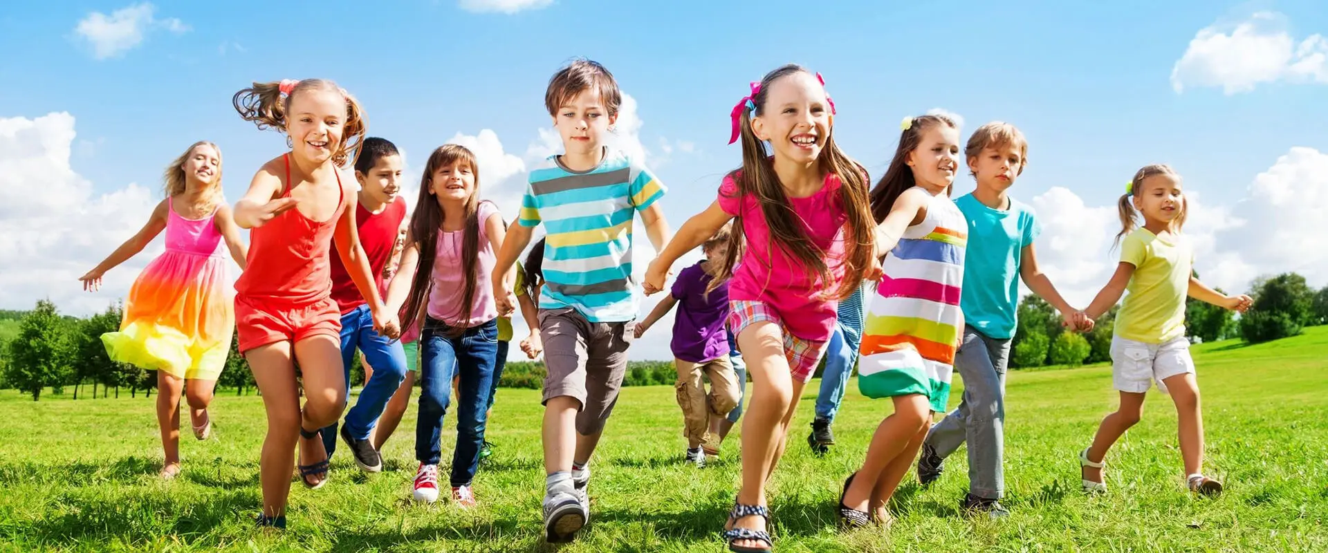 A group of children running in the grass.