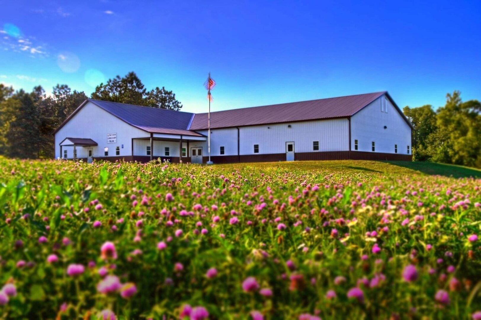 A large white building with pink flowers in the foreground.