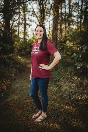 A woman standing in the woods posing for a picture.