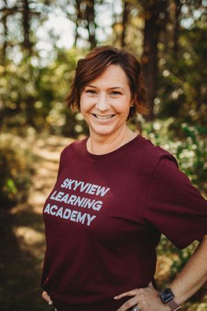 A woman in maroon shirt smiling for the camera.